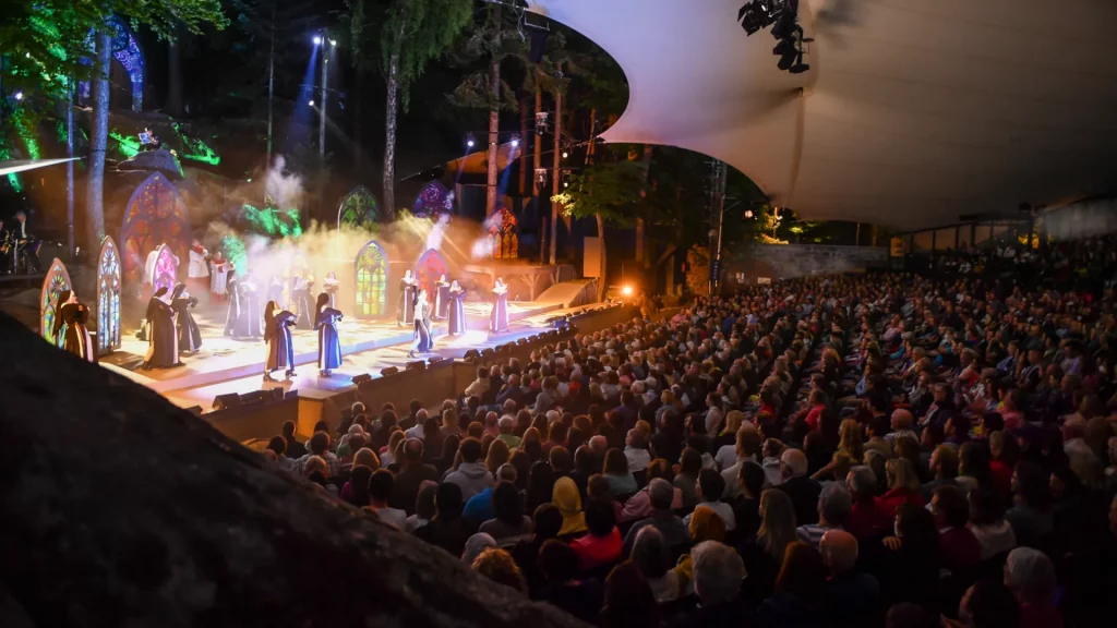 Links stehen Nonnen aus Sister Act auf der Bühne, rechts sieht man das Publikum, ca. 1.000 Menschen.